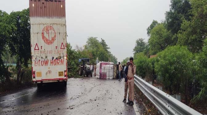 अयोध्या में लखनऊ हाईवे तेज आंधी के कारण पलटा वाहन कंटेनर; पेड़ से टकराया